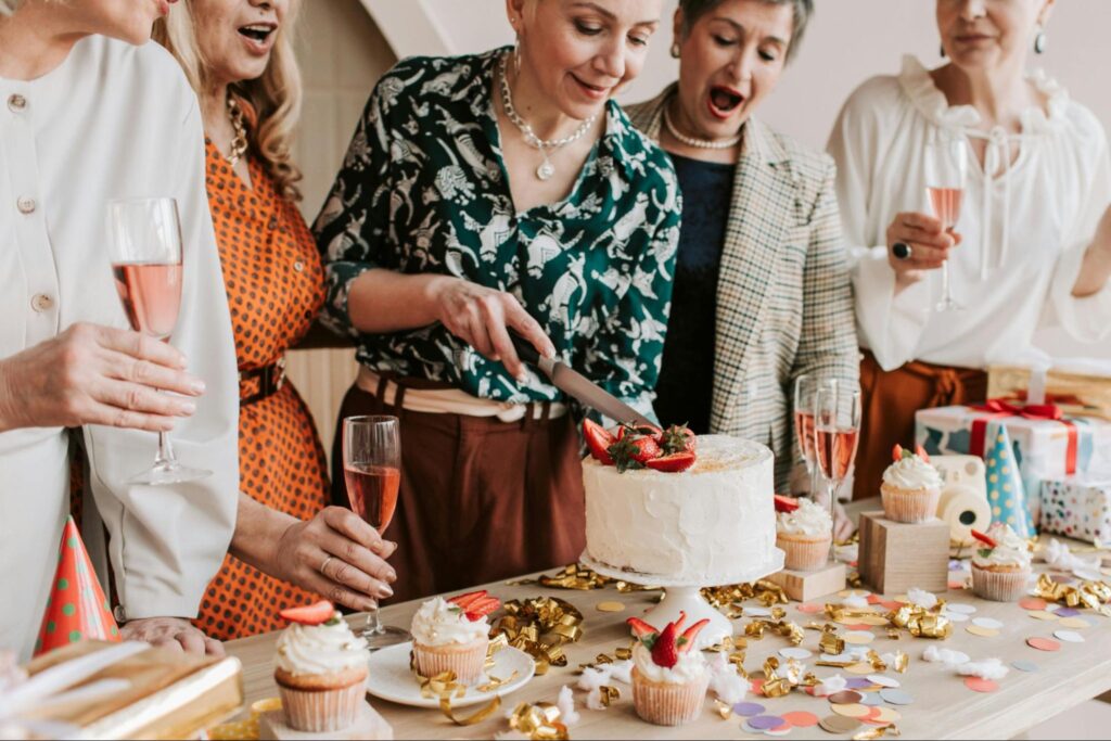 Coworkers cutting birthday cake at office celebration